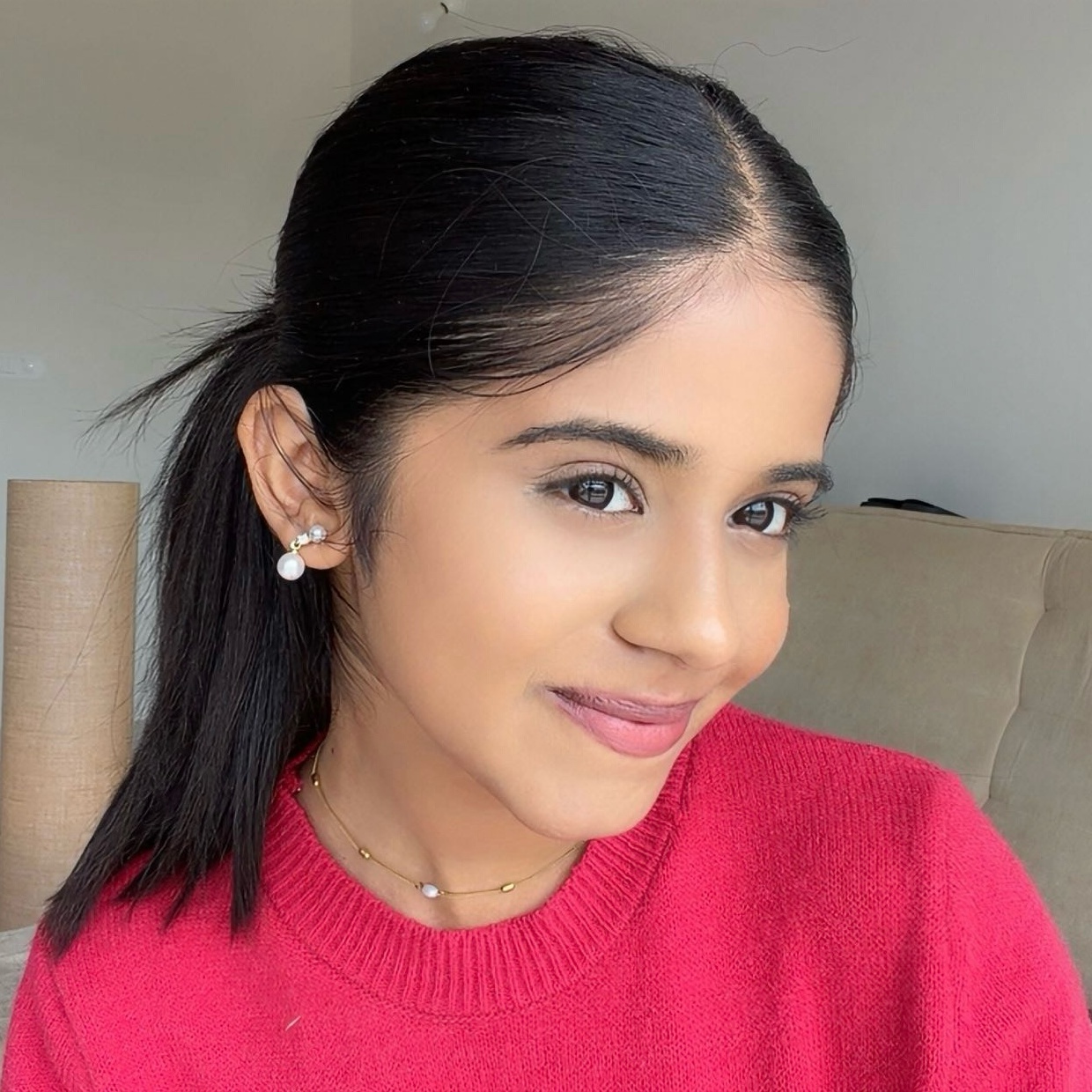 Harshitha smiling in a red sweater